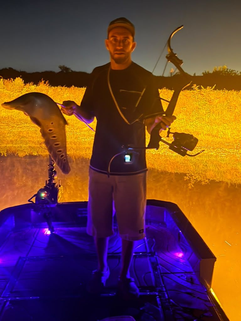 Native Roots Outdoors bowfishing trip photo with guests, fish, boat lights, and South Florida water