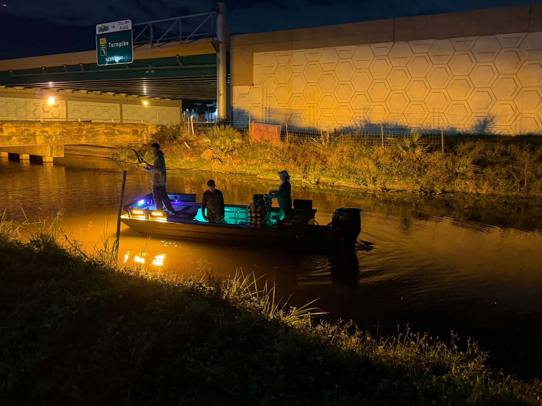 Native Roots bowfishing boat running under South Florida bridge lights at night